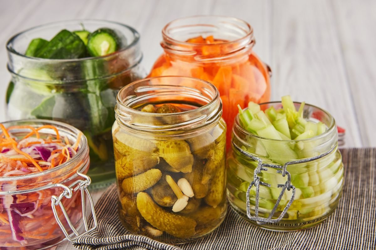 The image tells about jars with water and vegetables inside indicating that preserving extra food by pickling helps save money by keeping food fresh for months instead of letting it spoil.