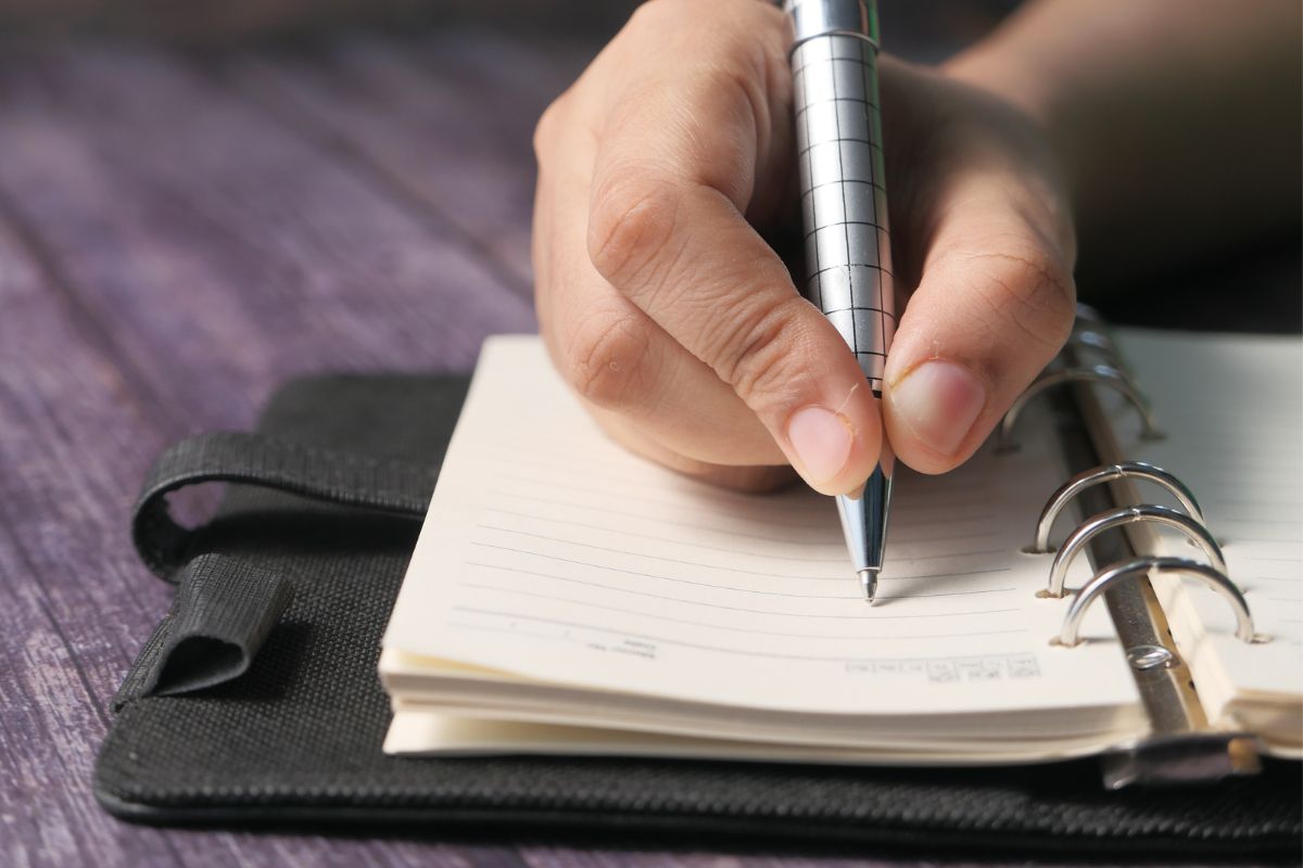 The picture shows a girl's hand and writing on the notebook which means that keeping a list of waste-free meal ideas makes meal planning faster and reduces the chance of being forgotten.