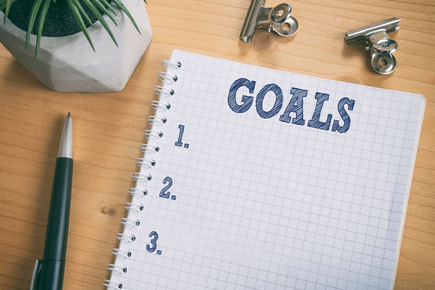 An image of a pen and a notebook with a goals list.