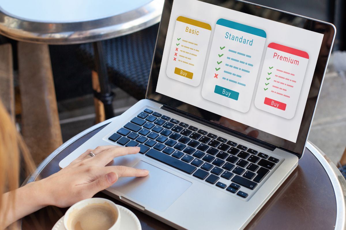 The photo shows a girl's hand using a laptop with a screen display while having a coffee referring to cutting out unnecessary subscriptions that can save money and put straight into savings instead. 