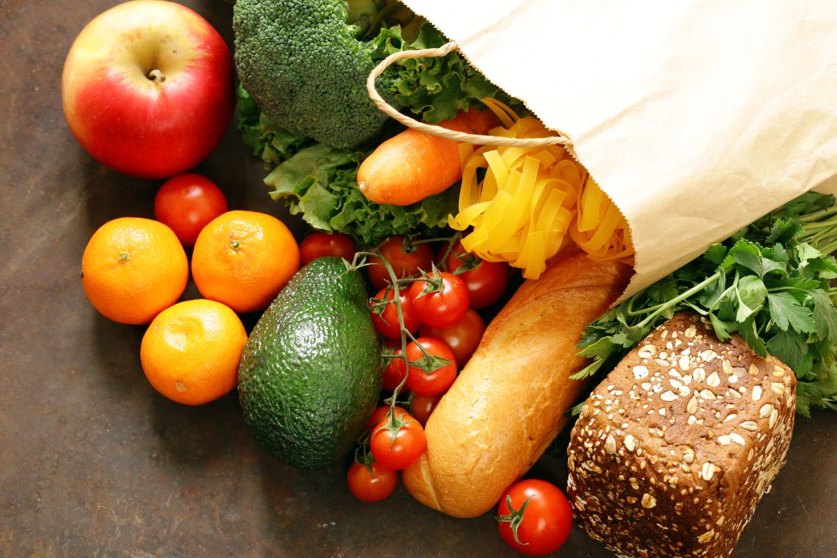 The picture tells about fruits, vegetables, and breads inside a paper bag indicating that doing a no-spend challenge helps reset spending habits and makes you think twice before buying things you don't need. 