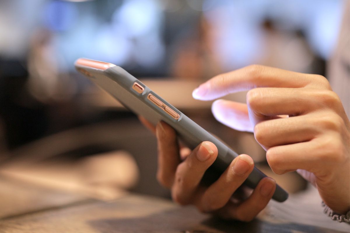 The picture shows a girl's hand using a phone which refers to rounding up transactions and saving the spare change is an easy way to save without thinking about it.