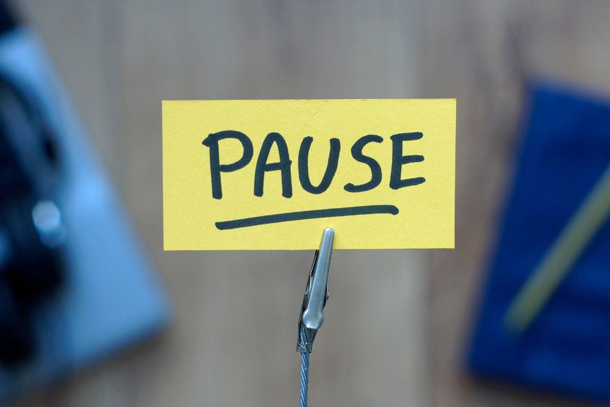 The photo shows a piece of paper with a note and clip referring to pause impulse spending helps stop wasteful spending and keeps money in your pocket.