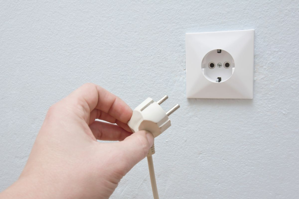 An image of a woman's hand unplugging a power cable.