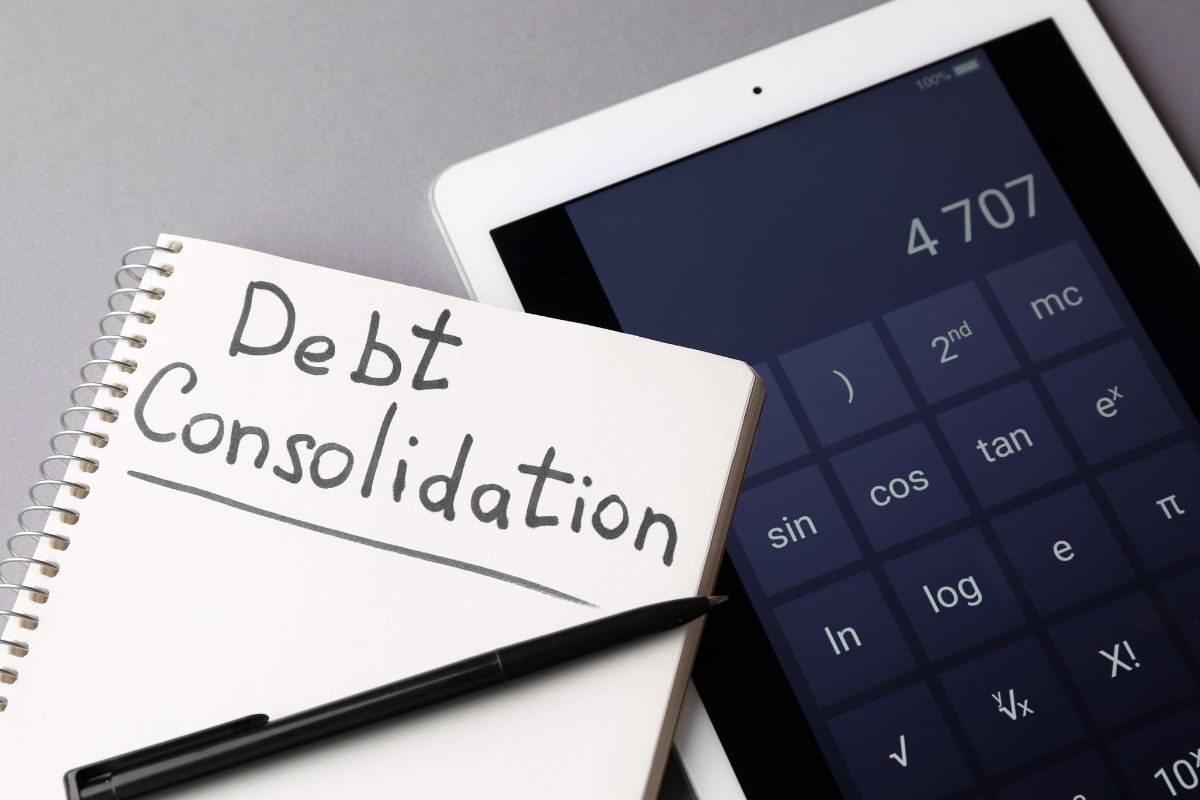 Picture of a digital calculator and a notebook with debt consolidation wording.