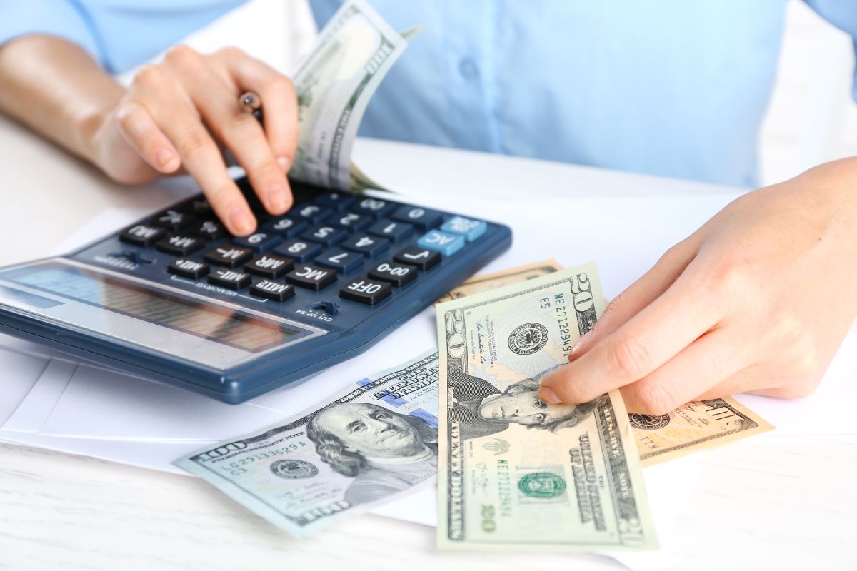 The picture shows a girl's hand calculating dollar bills indicating that tracking every dollar helps knowing where your money goes and helps you save faster.