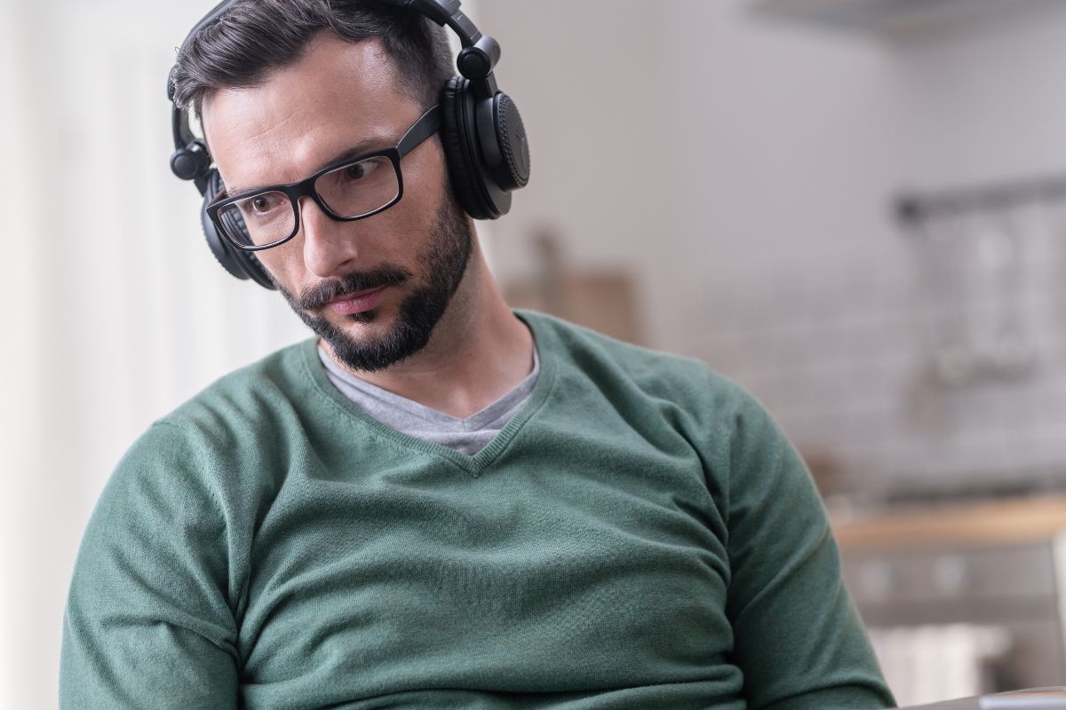 The photo shows a man listening to podcast.