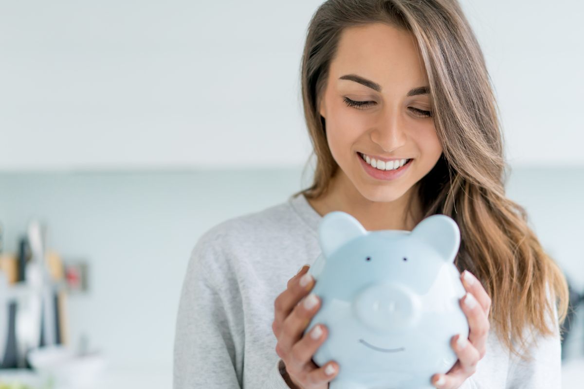 The image tells about a girl holding a piggy bank while looking at it referring to paying yourself first is one of the simplest ways to get rich.