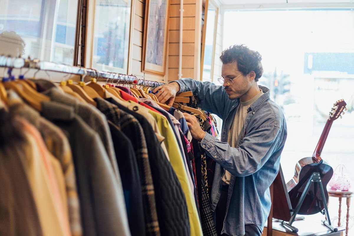 The photo shows a guitar display and a man choosing clothes on the display indicating that living below your means gives you control over your money.
