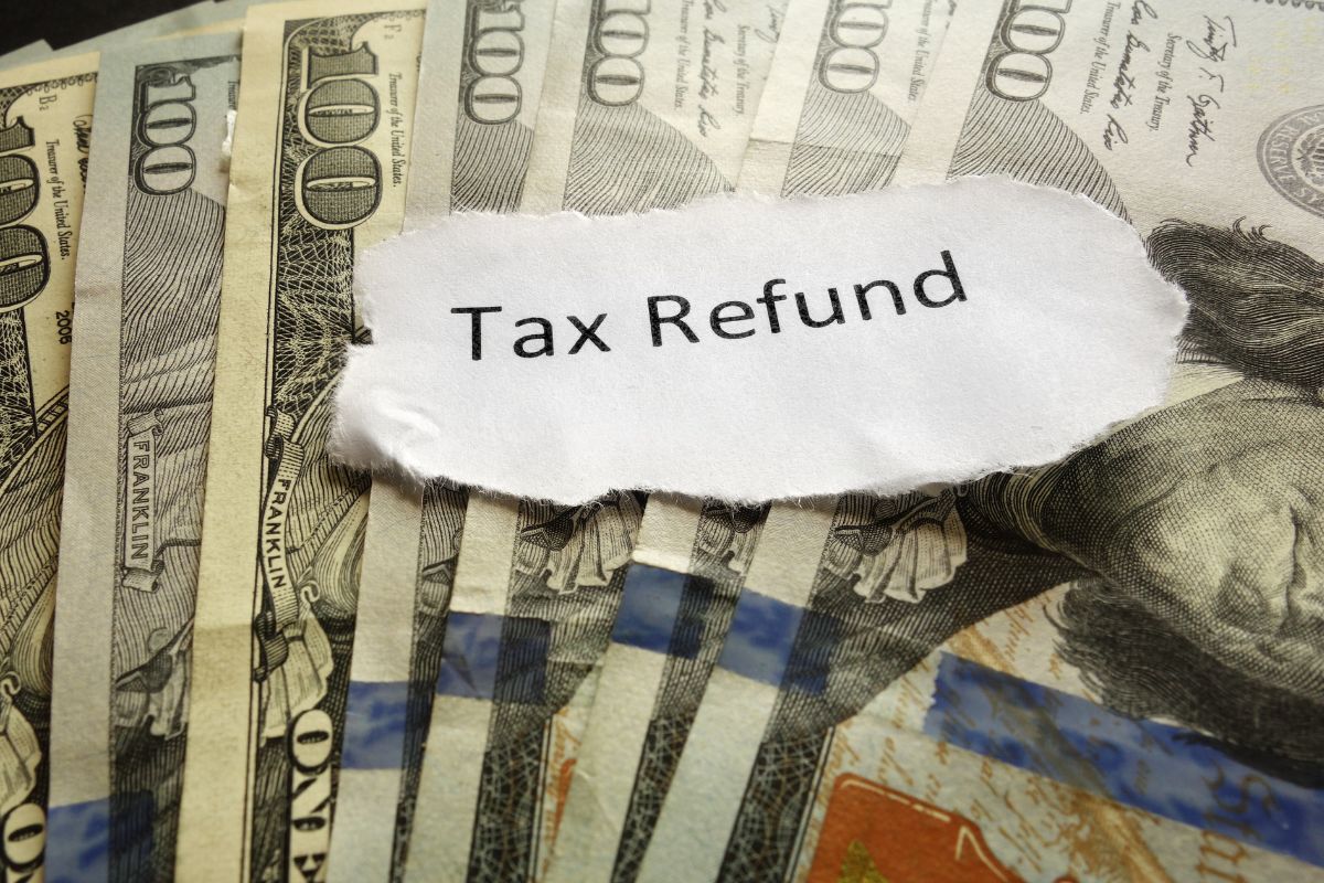 The picture shows dollar bills and a piece of paper with notes which means saving windfalls builds wealth without changing daily habits.