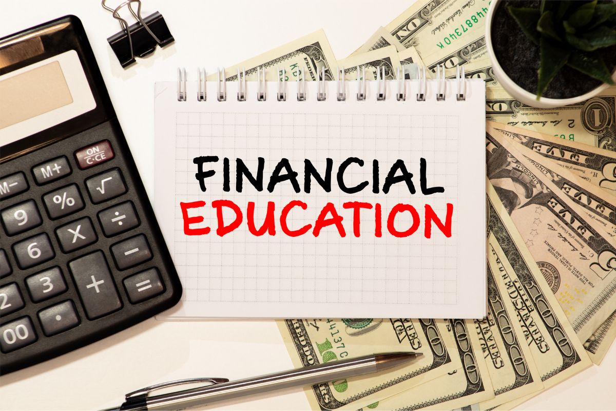 The picture shows a calculator, a plant, a pen, dollar bills, and a notebook with notes which means that staying educated on finance helps avoid costly mistakes and grow wealth faster.