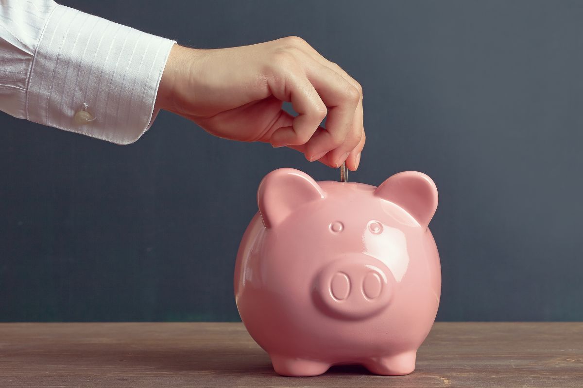 The picture shows a man's hand putting a coin into it indicating to save money fast even on low income that can lead to big financial wins in the future.