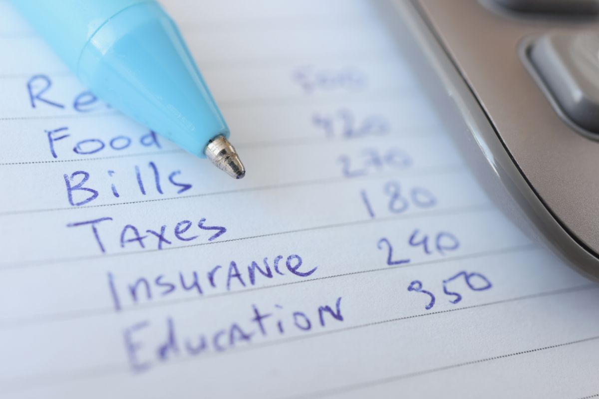 The image shows a calculator, a pen, and a paper with notes which means listing all fixed expenses makes it easier to figure out how much money is left for everything else.