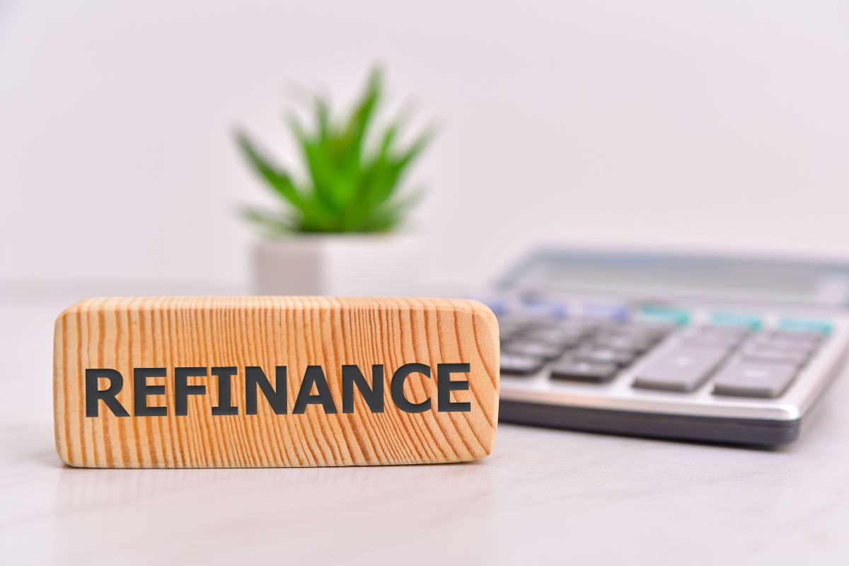 The photo of a calculator and wooden with refinance wording.