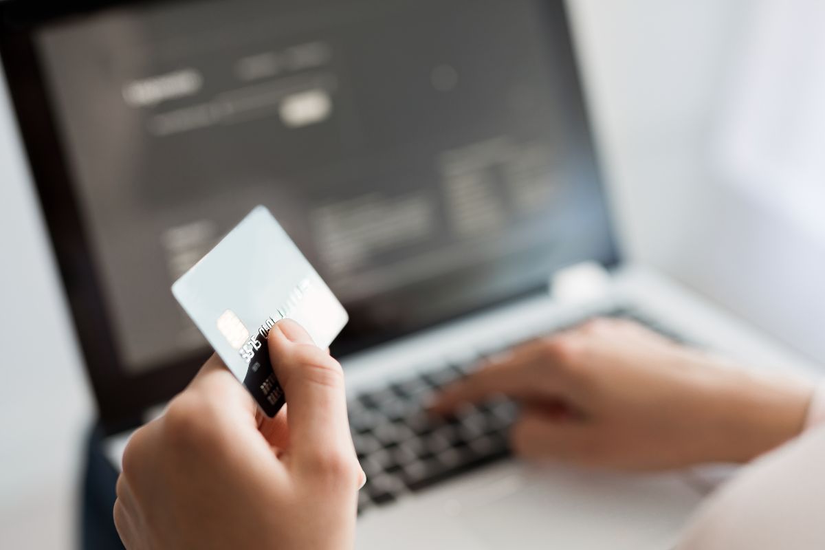 The image tells about a girl's hand typing on the laptop while holding a card which means automated fixed payments keep things simple and avoid missed deadlines.