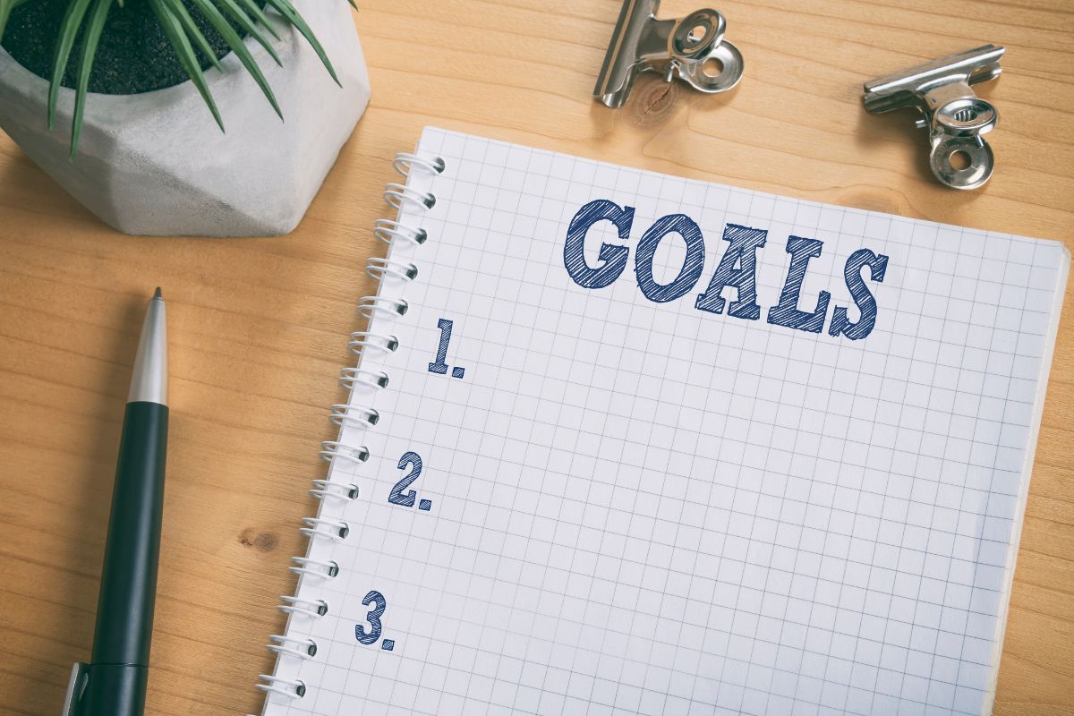The picture shows a pen and a notebook with goals wording.