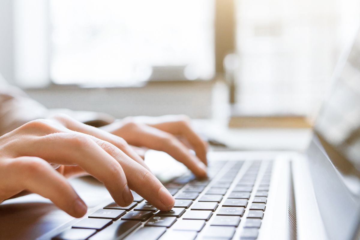 The photo shows a girl's hand typing on the laptop indicating to sell Ad space on a Niche Website is a great way to earn passive income.