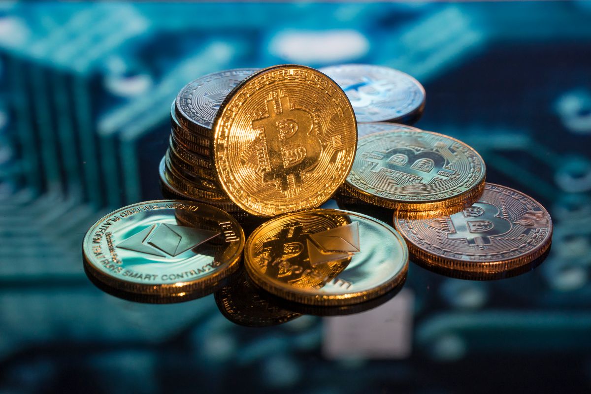 The picture shows coins with signs referring to setting up passive income through crypto staking is a hands-off way to build wealth over time.