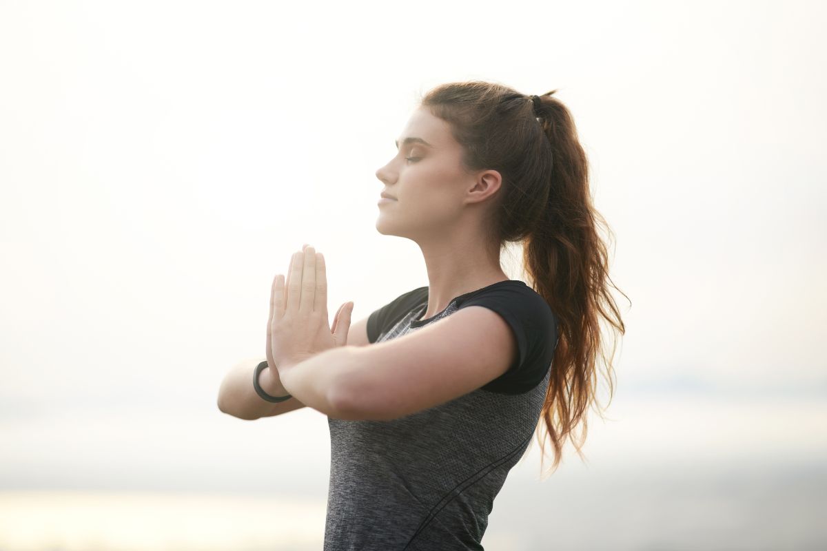 The photo shows a girl praising both hands and relaxing referring to cultivating a mindset of abundance helping focus on opportunities instead of limitations.