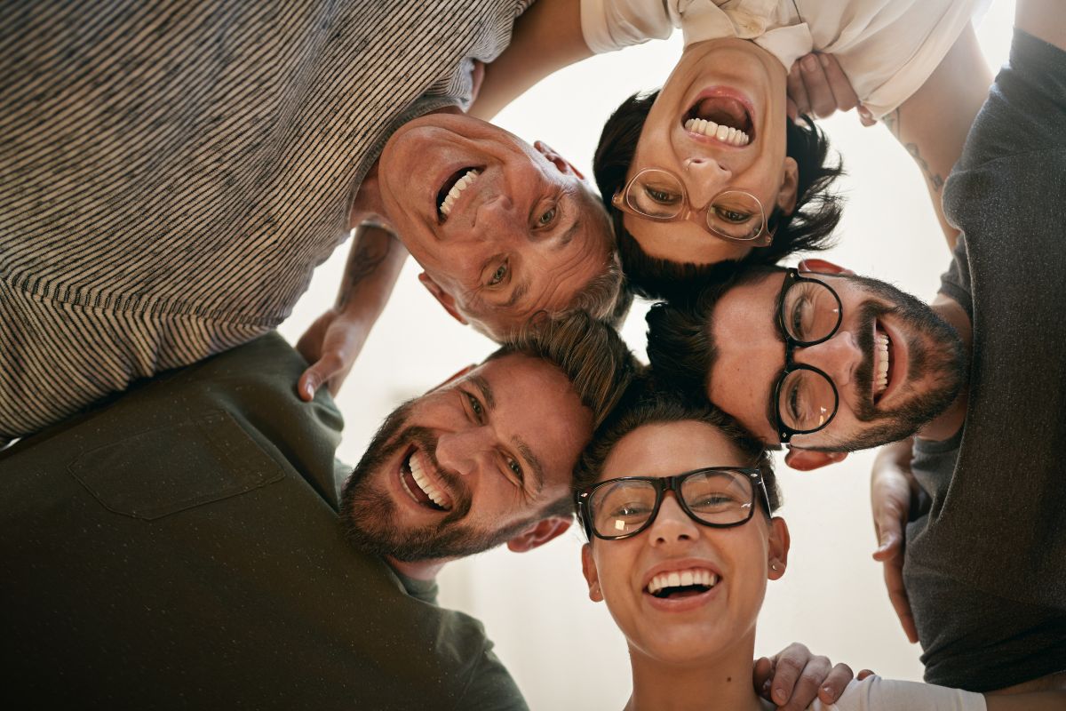 The image of a group of people joining their heads together indicating to surround yourself with like-minded grateful individuals makes it easier to stay positive about wealth building.