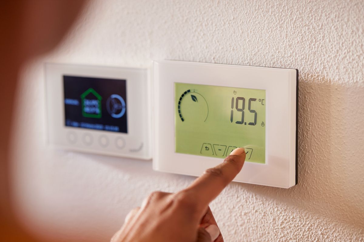 The picture of a woman adjusting the thermostat.