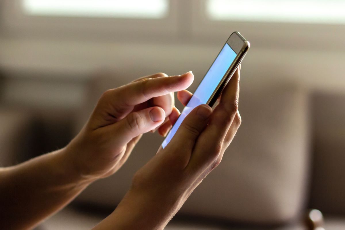 The image shows a girl's hand using a phone indicating that a downgrade phone can save money without a noticeable difference in service.