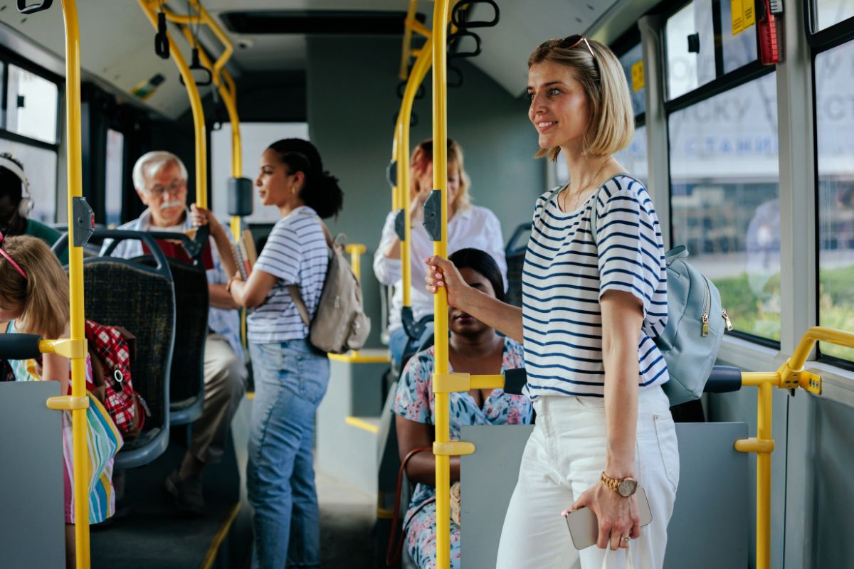 The picture shows a group of people inside the bus which refers to how using public transportation can lower expenses and save money.