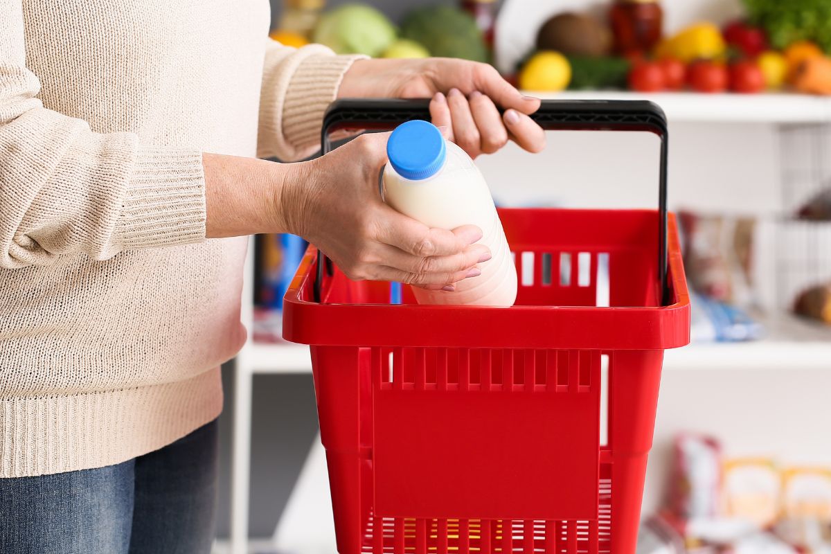 A photo of a woman buying a bottle of milk.