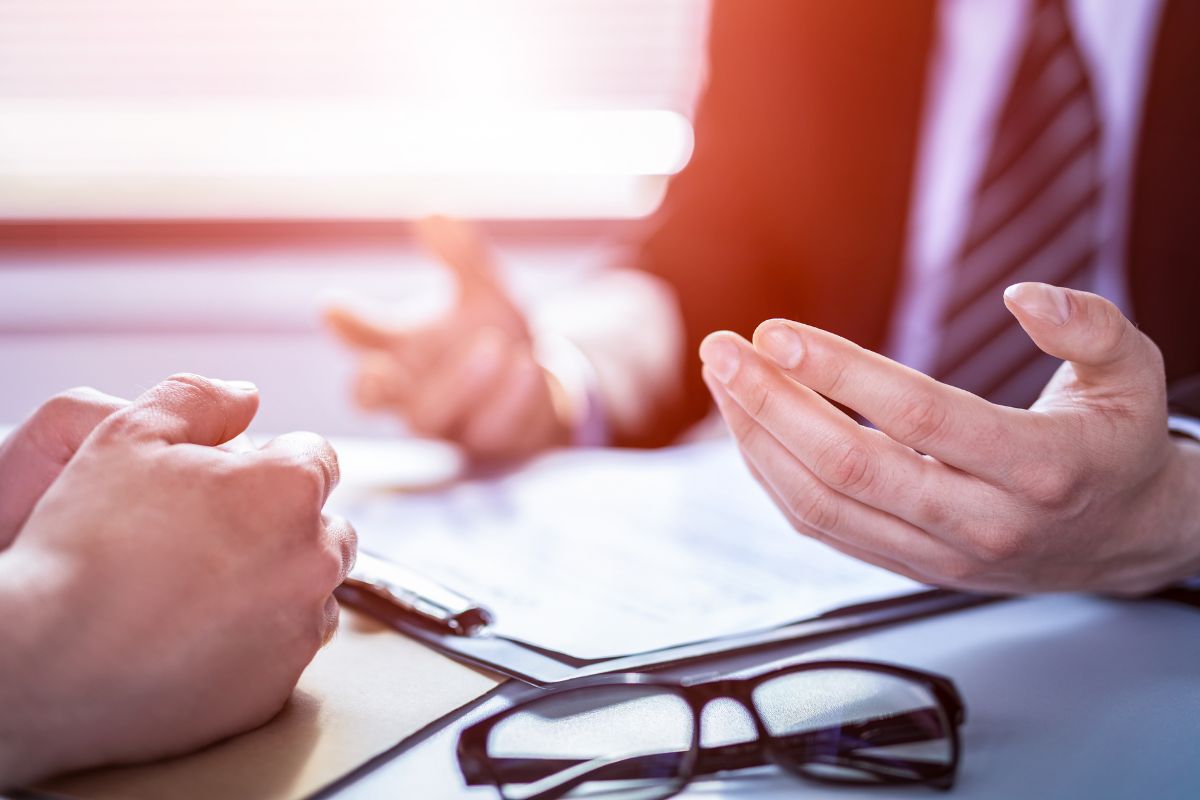 The photo shows an eyeglass, a clipboard, and two men talking referring to negotiating bills like insurance can save money a month.