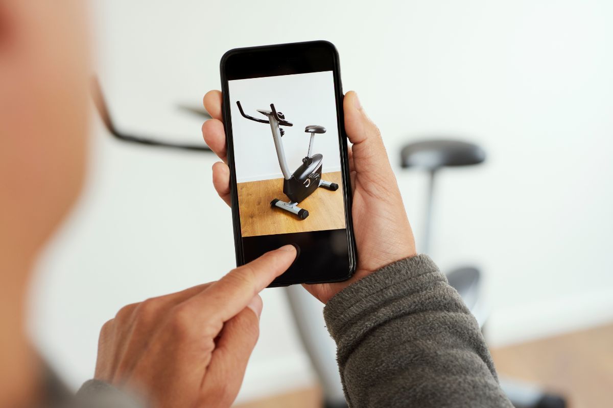 The picture shows a man taking a photo on the exercycle to sell unused items inline for extra cash is a simple way to boost savings.