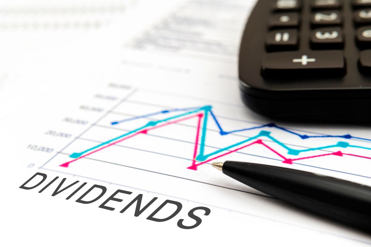 The photo tells about a calculator, a pen, and a piece of paper with notes and a graph referring to dividend stocks is a great for those who want long-term financial growth without daily involvement.