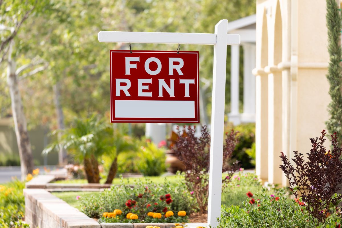 The picture shows a garden, concrete, and signage which refers to investing in rental properties for monthly income, one of the most reliable ways to generate passive income.