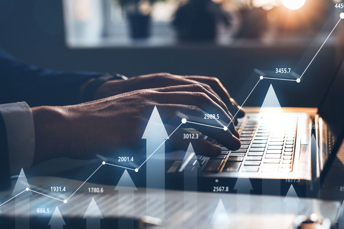 The image tells about a man's hand using a laptop with visual arrows and numbers on the screen referring to trade long-term options is a good choice for those who want to grow wealth without constant buying and selling.