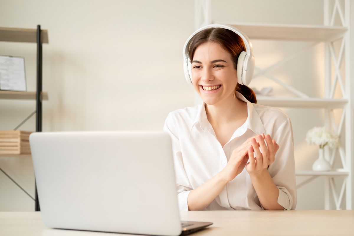 The image shows a girl using a headphone while looking at the laptop referring to launching online coaching is a great way to make money while helping others succeed.