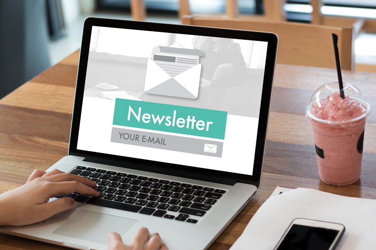 A woman's hand using a laptop with a newsletter display.