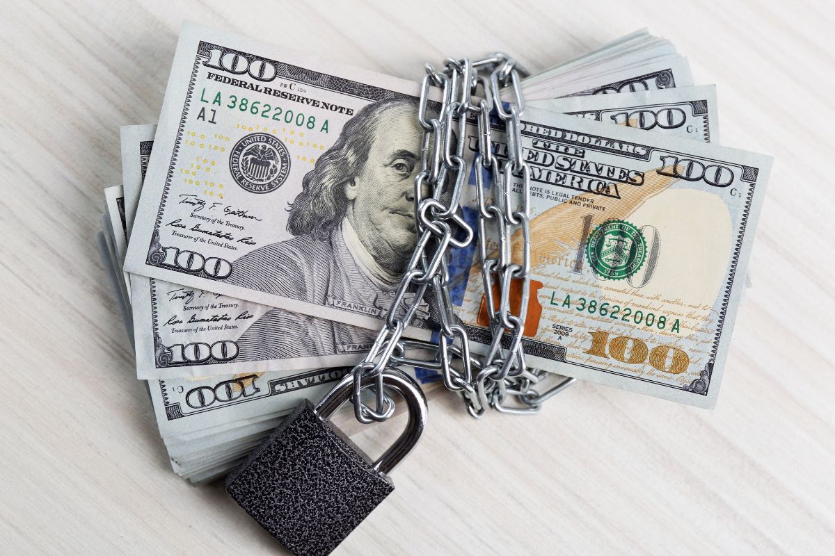 The image shows dollar bills with chains and padlock which means a financial security that gives peace of mind and keeps unexpected expenses from causing stress.