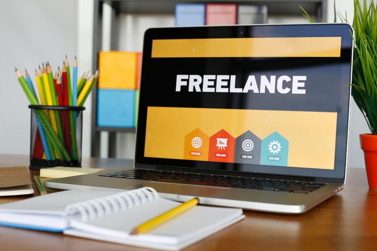 The picture shows pens, a notebook, a pen, and a laptop with a screen display referring to freelancing on online platforms is an easy way for beginners to start making money online without needing a big investment.