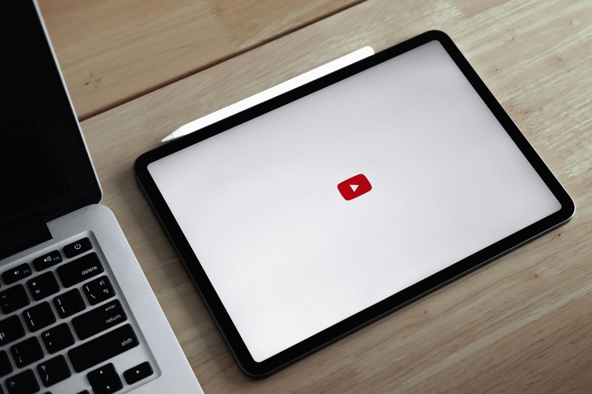 The photo tells about a laptop and a tablet device with an icon and a digital pen indicating that starting a YouTube channel and monetizing with can be a good way to make money if you enjoy creating videos.