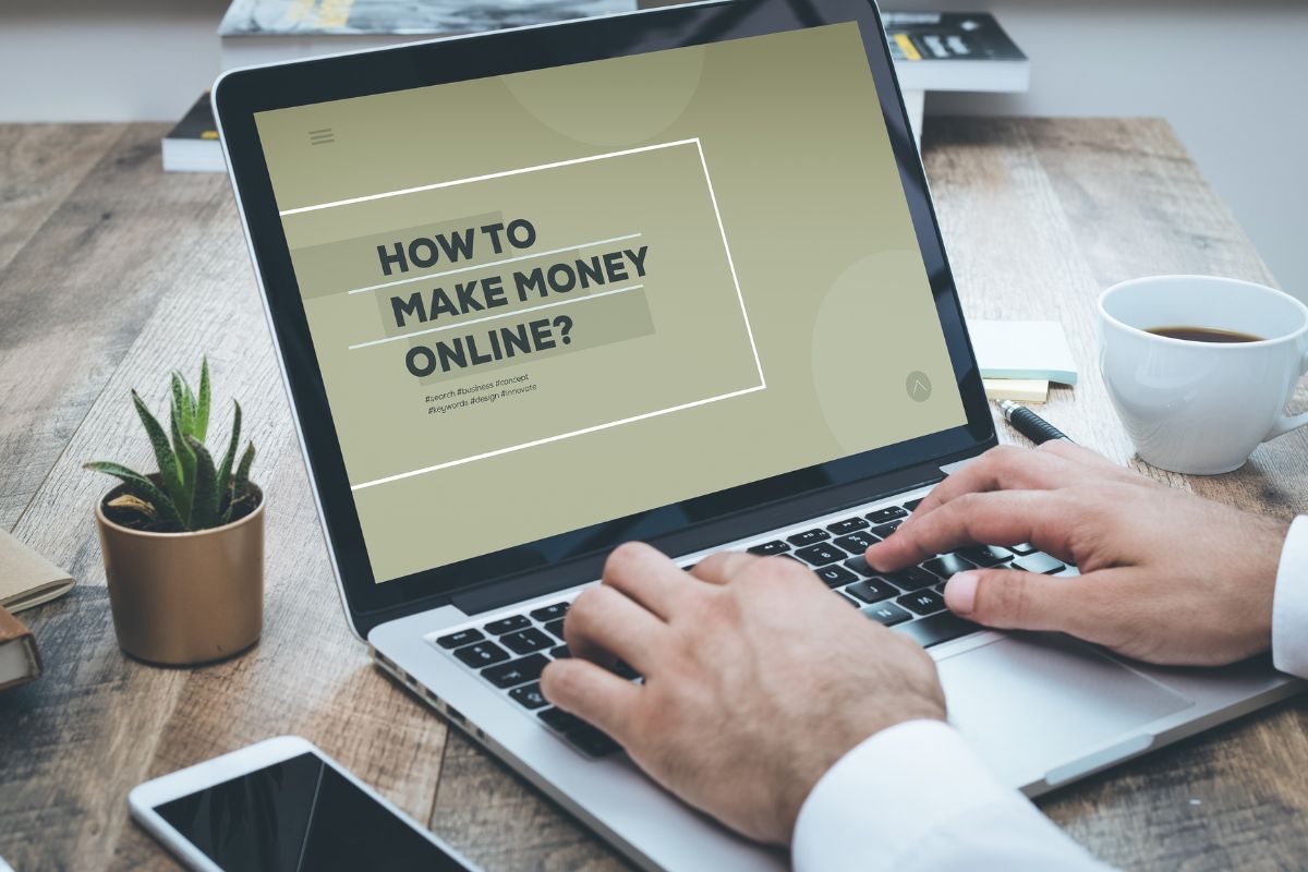 The photo tells about a coffee, a plant, a phone, and a man's hand using a laptop with a screen display indicating to get trained to make money online beginners can turn a simple side hustle into a steady source of income.