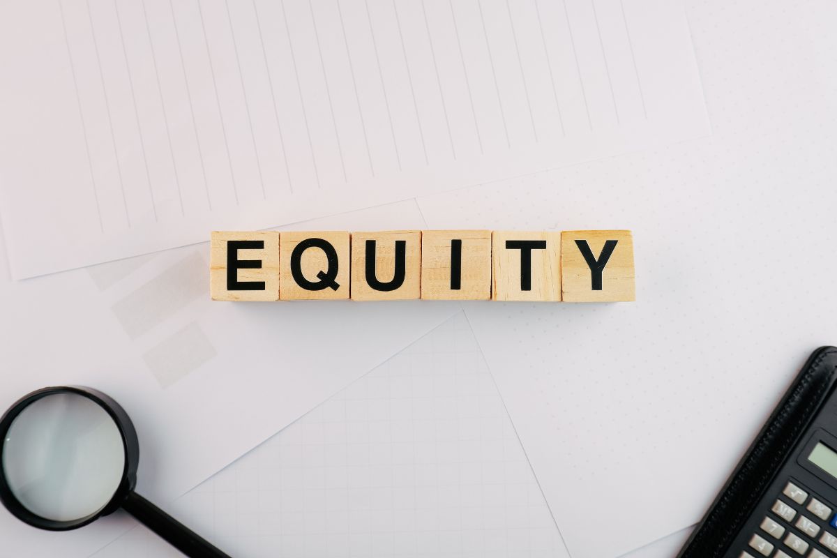 The image shows a magnifying glass, a calculator, and wooden cubes with letters referring to how much equity I have in my home to help determine if refinancing is a smart financial move.