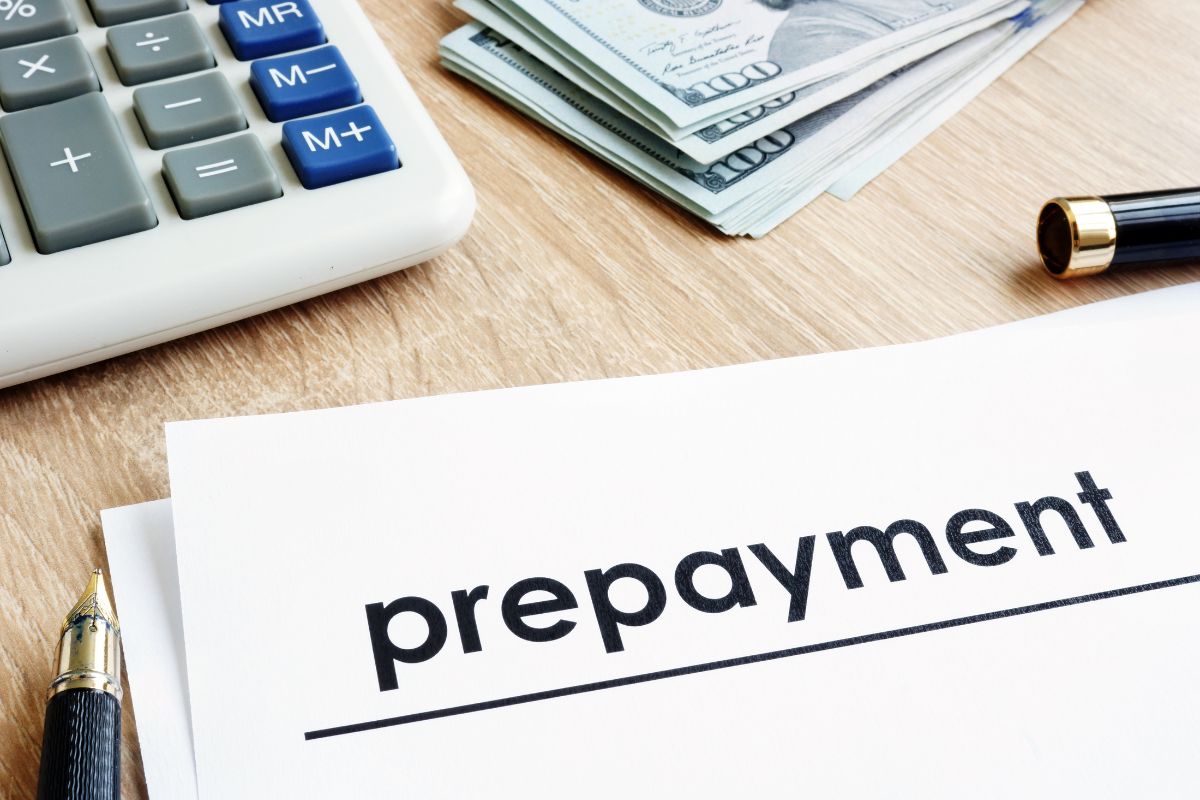 The photo of a calculator, dollar bills, a pen, and papers with a note referring to knowing if there are prepayment penalties on your current mortgage helps you make a smarter decision.