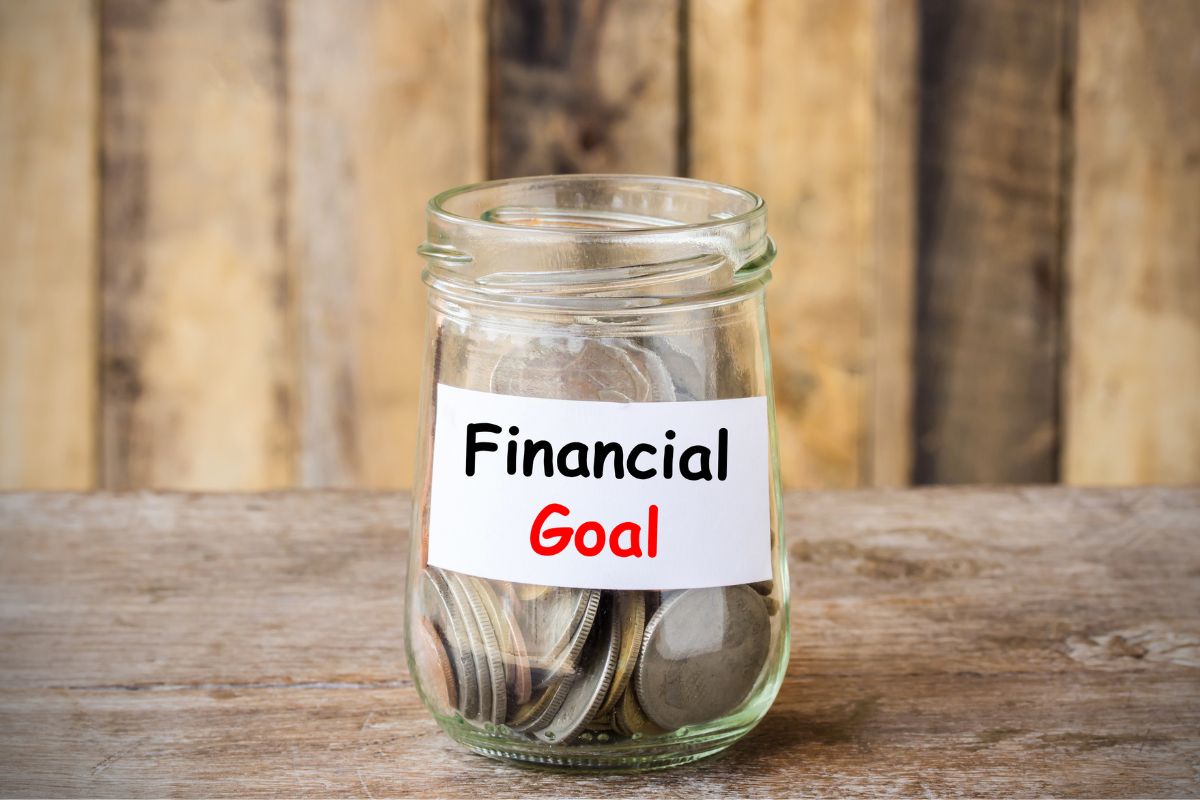 The image shows a jar filled with coins and notes referring to refinancing impact for overall financial goals to make sure the new loan aligns with your financial priorities before making a move.