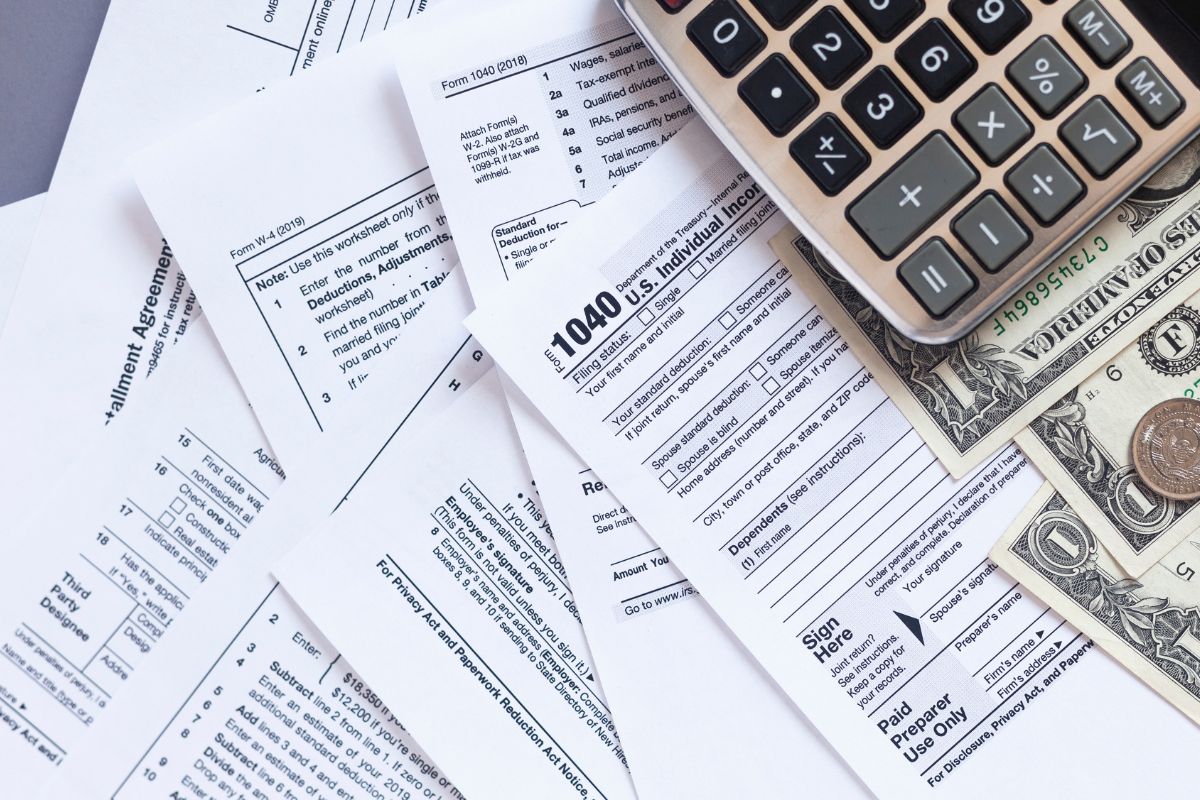 The image shows a calculator, dollar bills, a coin, and papers with notes referring to how will refinancing affect my taxes, knowing this ahead of time helps you avoid surprises.