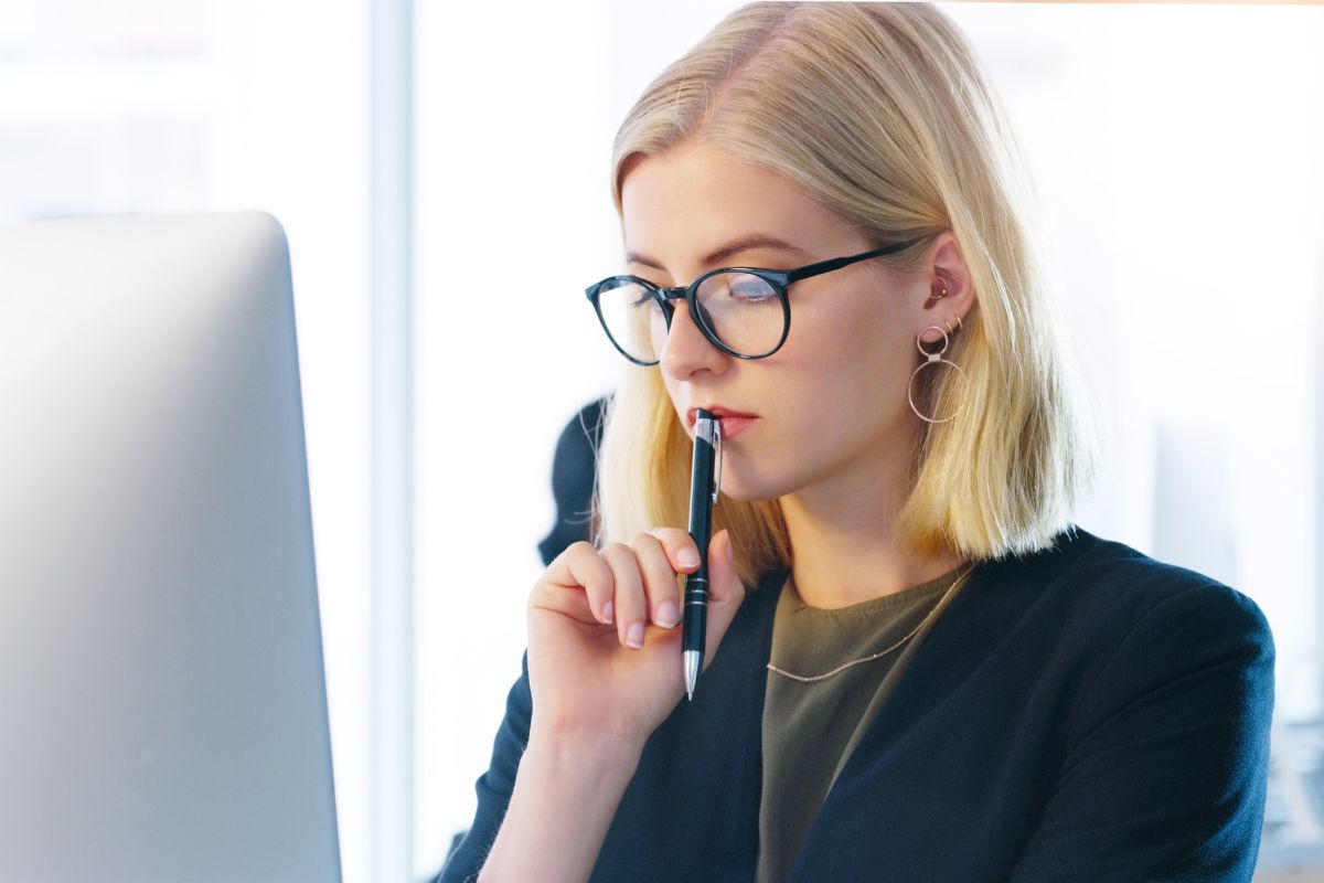 The image shows a girl thinking while looking at the monitor with a pen on which refers to risk tolerance and decision-making, a balanced approach helps you make smart decisions while managing potential downsides.
