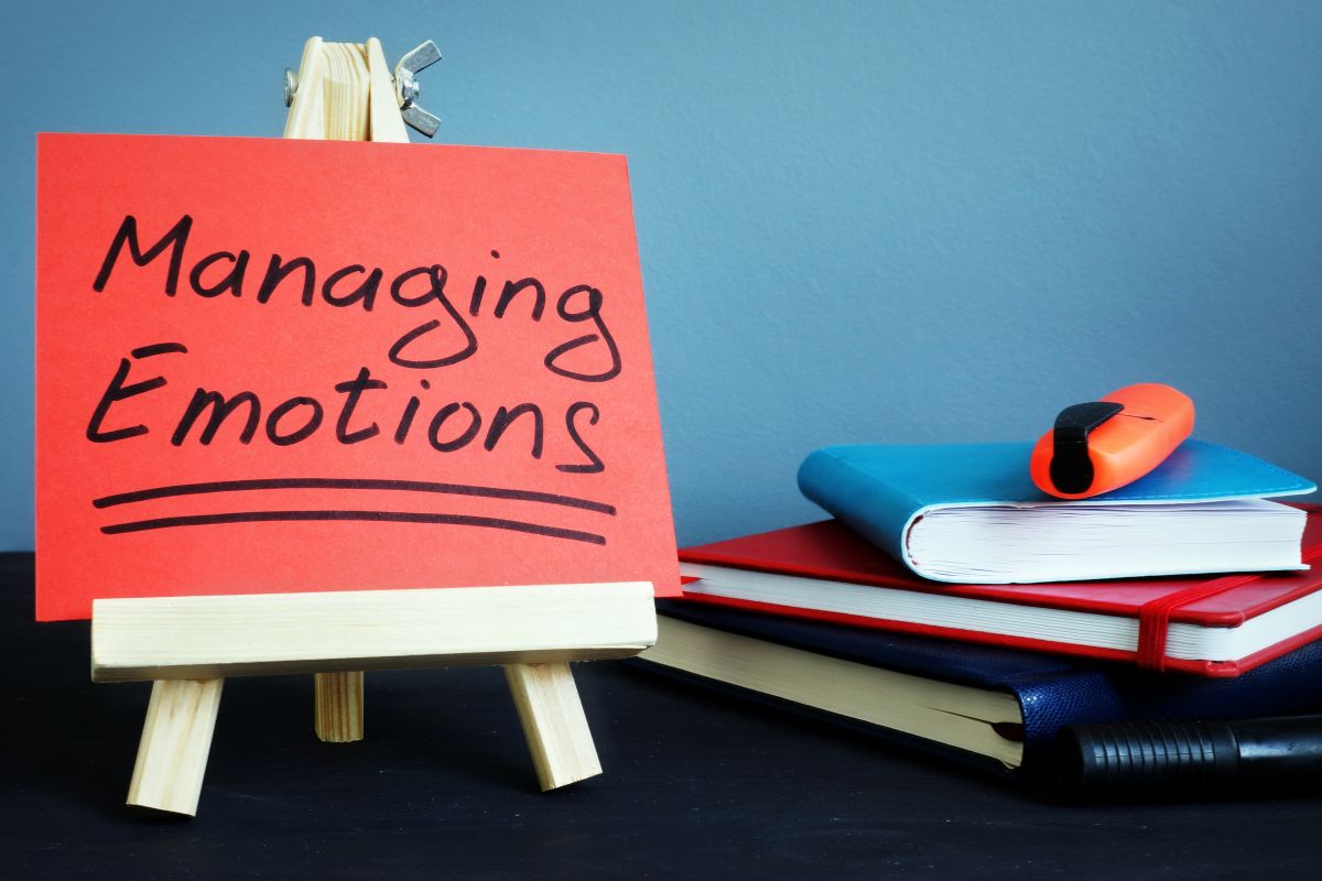 The photo shows notebooks, a marker, a cutter, and a board with notes referring to emotional control over spending helps you separate wants from needs and focus on what truly matters.