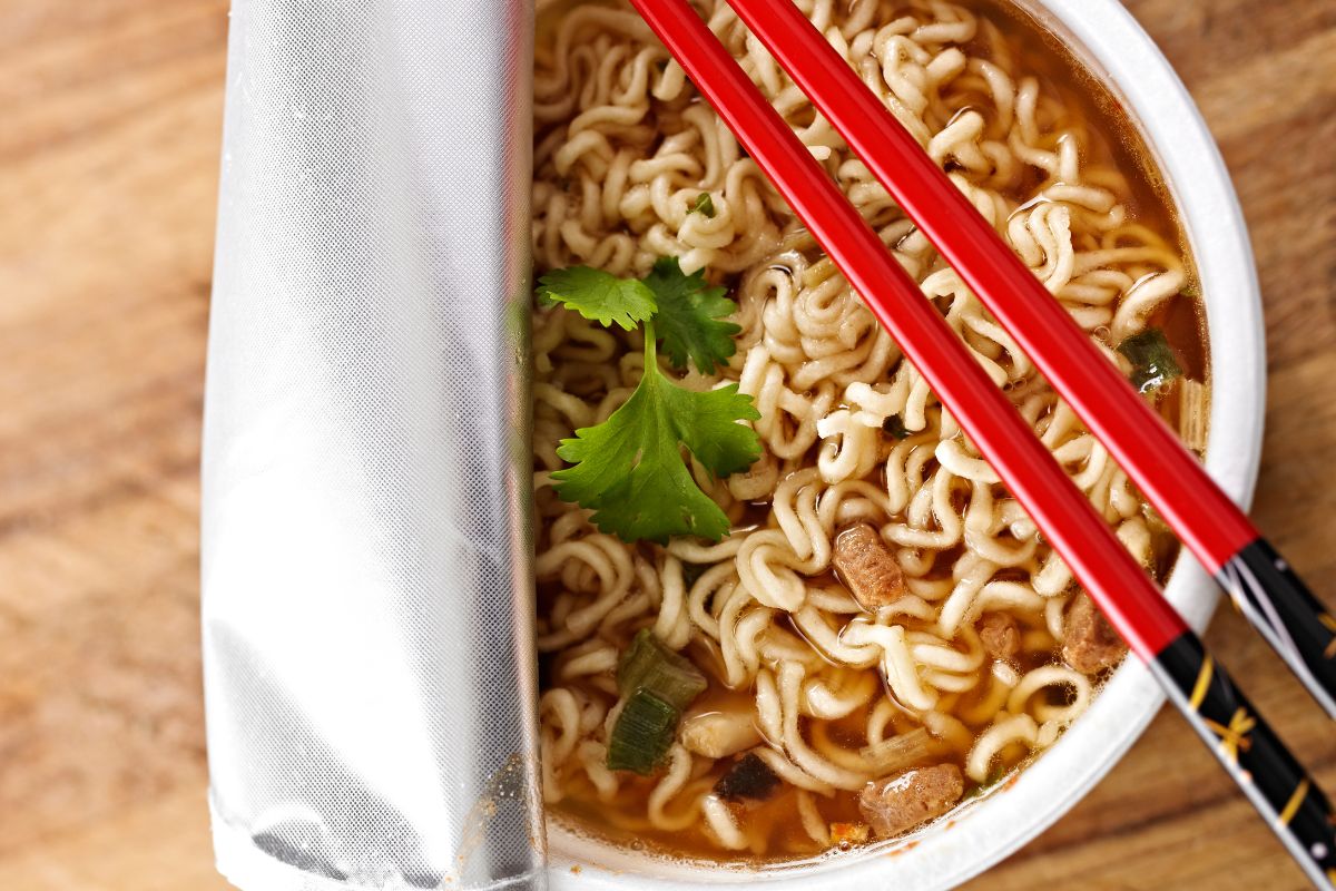 The photo shows a cup with noodles and a chopstick referring to instant noodles may be cheap but they don't provide real nutrition.