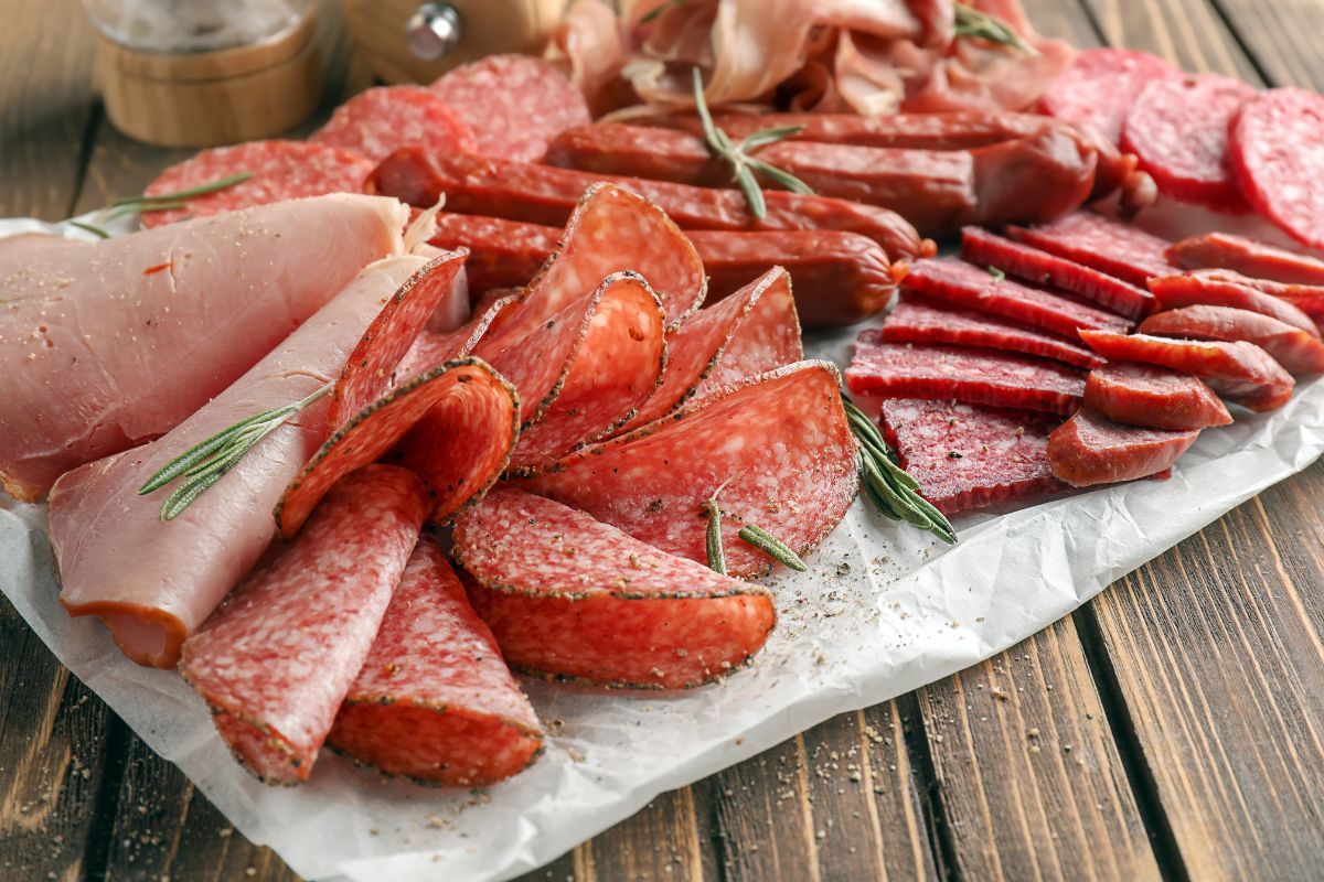 The image shows sliced meats on the table referring to deli meats and processed sausages are expensive for what you get and are labeled with preservatives.