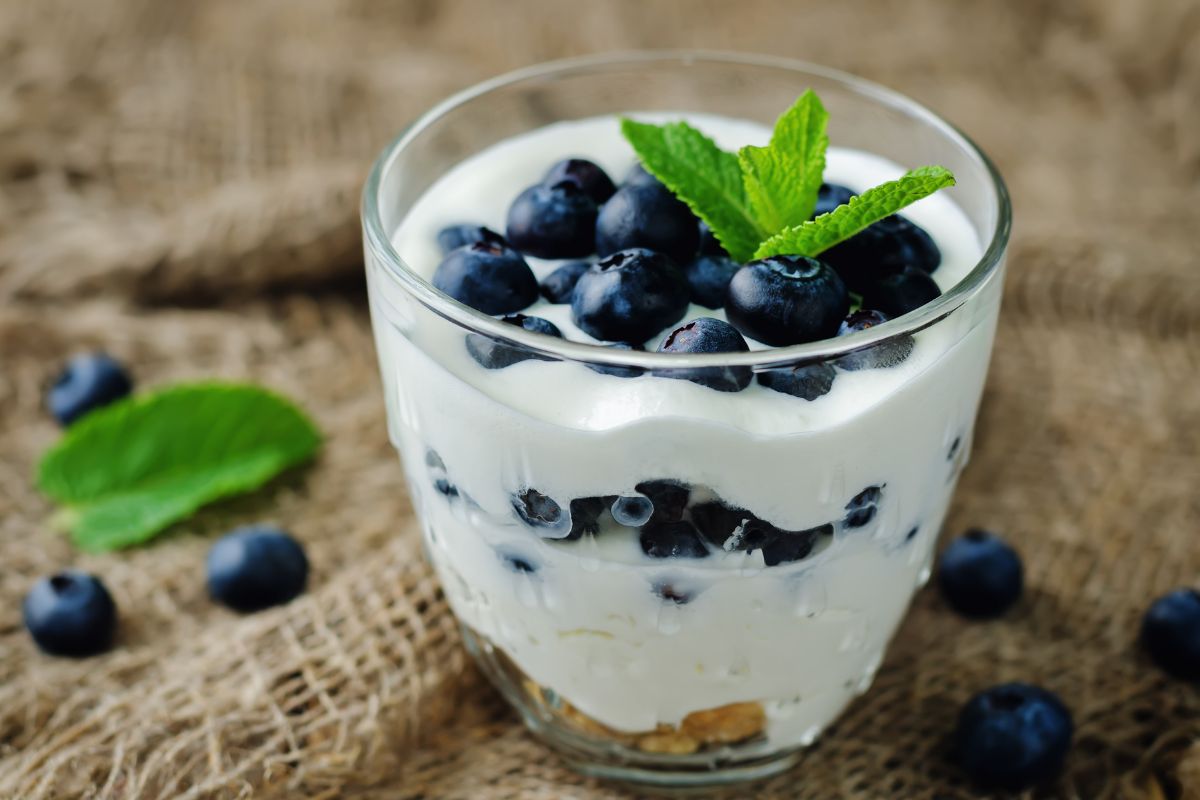 The photo of blueberries and glass with yogurt and blueberries indicates that flavored yogurts cost more than plain options.
