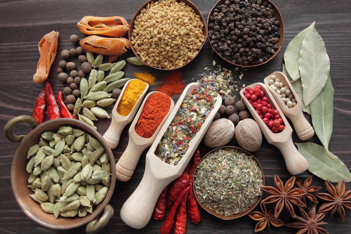 The picture of different kinds of spices in containers and on the table which refers to fancy spice blends often overpriced and full of fillers, keeping simple helps keep grocery costs down.