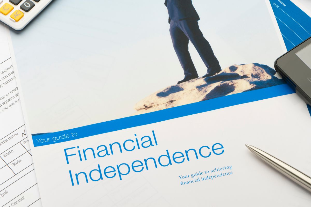 The picture shows a calculator, a phone, a pen, and a piece of paper with images and notes referring to defining your long-term financial goals to stay focused and make decisions that move you closer to financial stability.